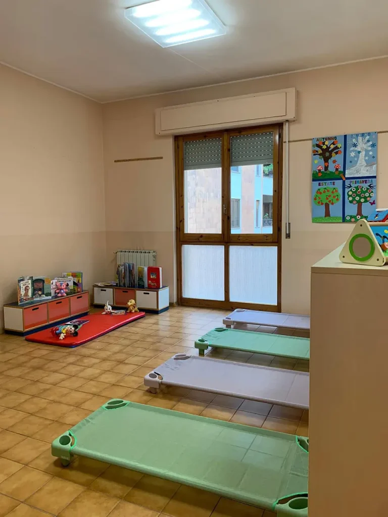Angolo lettura della Sezione Primavera con libri illustrati, giochi educativi e spazio morbido per bambini dai 24 ai 36 mesi.