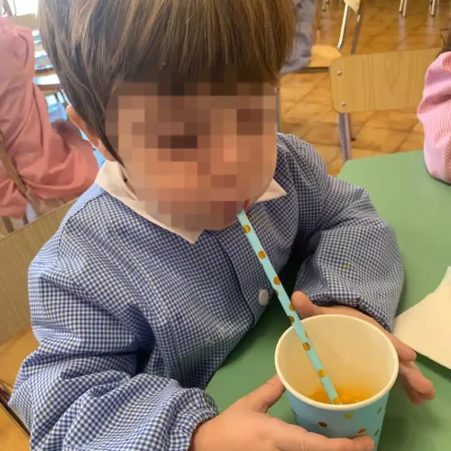 Bambino gusta una merenda a base di succo di frutta durante una pausa nella scuola dell'infanzia.