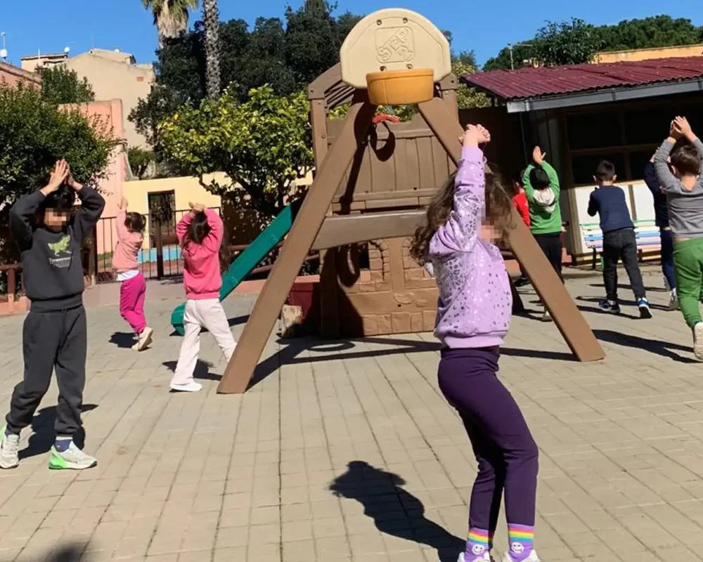 Bambini svolgono esercizi di psicomotricità nel giardino della Scuola dell'Infanzia Provvidenza Sacro Cuore.